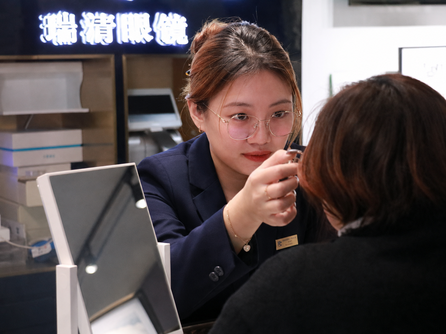 瑞清验配人员穿藏蓝色职业装为顾客核对镜架位置
